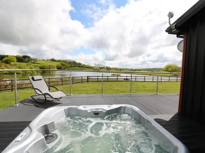 a bath tub sitting on a deck with a chair at Llyn Cae Ty Nant Fishery Holiday Let in Lampeter