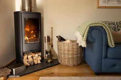 a living room with a blue couch and a fireplace at Romantic Snowdonia Cottage with Hot tub, sea & mountain views in Tywyn