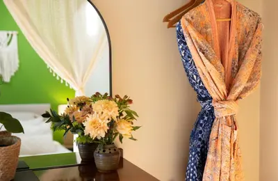 a dress hanging on a wall with flowers on a table at Romantic Snowdonia Cottage with Hot tub, sea & mountain views in Tywyn