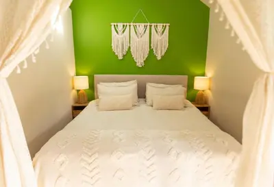 a bedroom with a white bed with a green wall at Romantic Snowdonia Cottage with Hot tub, sea & mountain views in Tywyn