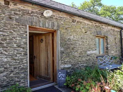 a brick building with a door and a bench outside at Golwg Las in Llanwrda
