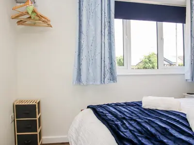 a bedroom with a bed and two windows at Little Oakleigh in Llanymynech