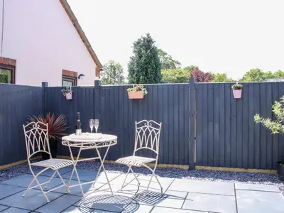 a patio with a table and two chairs and a fence at Little Oakleigh in Llanymynech