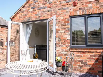 a brick building with a patio with a table and chairs at Little Oakleigh in Llanymynech