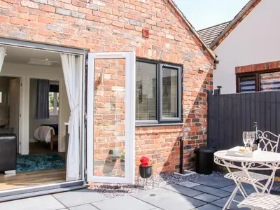 an open door to a brick house with a patio at Little Oakleigh in Llanymynech