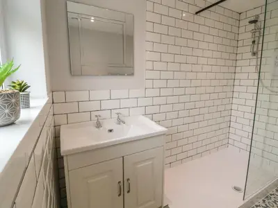 a white bathroom with a sink and a shower at Bryn Teg in Oswestry