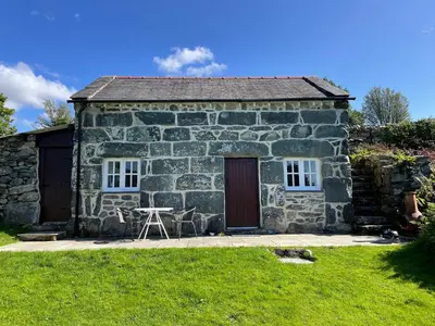 a stone cottage with a table and chairs in front of it at Gelli Bach at Gelli Las in Llanbedr