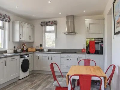 a kitchen with white cabinets and a table and chairs at Bryn Y Felin in Dyffryn