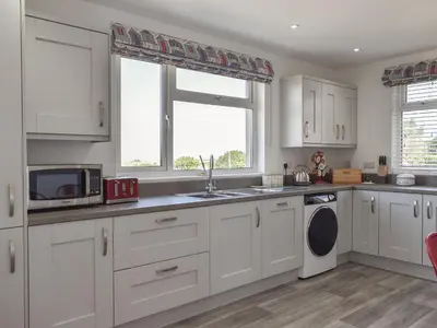 a kitchen with white cabinets and a sink and a window at Bryn Y Felin in Dyffryn