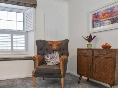 a chair with a pillow in a room with a dresser at Bryn Y Felin in Dyffryn