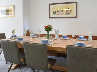 a dining room table with chairs and a wooden table with flowers at Bryn Y Felin in Dyffryn