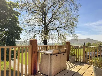 a wooden deck with a table and a fence at The Red House - Uk39234 in Minsterley