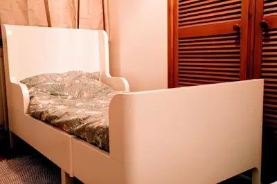 a white bed in a room with a wooden cabinet at Hillside Cottage, countryside views near Llangollen in Corwen