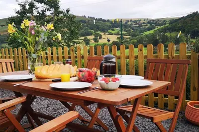 a wooden table with food on top of a fence at Hillside Cottage, countryside views near Llangollen in Corwen