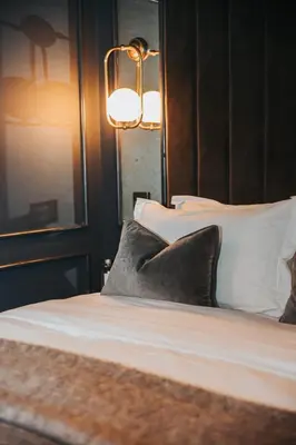 a bedroom with a bed with pillows and a lamp at Y Seler in Aberaeron