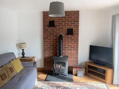 a living room with a brick fireplace with a stove at 3 Bedroom Bungalow in Llanrhaeadr Ym in Oswestry