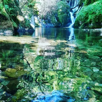 a river with a waterfall in the background at Spacious heated Yurt with Hot tub, 5 mins to beach in Bow Street