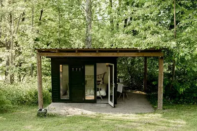 a small cabin with a deck in the woods at Stay Wild Retreats 'Glamping Pods and Tents' in Wrexham