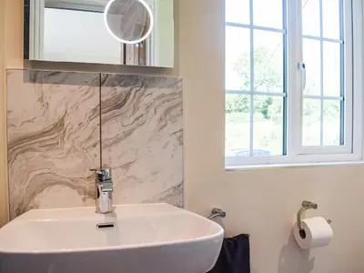 a white sink in a bathroom with a window at Barnleigh in Ludlow