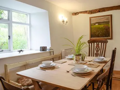 a wooden table with plates and bowls on it in a dining room at Lower Goytre Farmhouse in Llanvair Waterdine