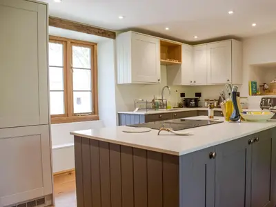a kitchen with white cabinets and a counter top at Lower Goytre Farmhouse in Llanvair Waterdine