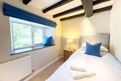 a bedroom with a bed with blue pillows and a window at Marrington Mill in Chirbury