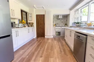 a kitchen with white cabinets and a wooden floor at Marrington Mill in Chirbury