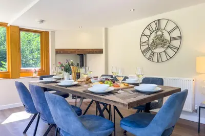 a dining room with a wooden table and blue chairs at Marrington Mill in Chirbury
