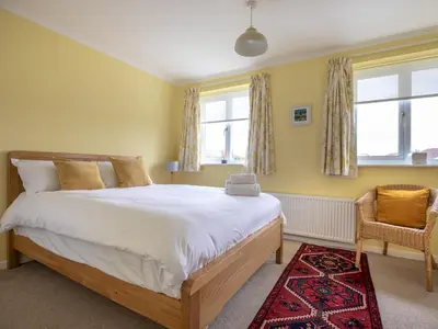 a bedroom with a large bed and two windows at Cheerful and modern one bedroom home with parking - Pass the Keys in Shrewsbury