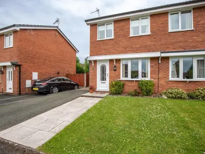 a brick house with a car parked in the driveway at Cheerful and modern one bedroom home with parking - Pass the Keys in Shrewsbury