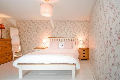 a bedroom with a white bed with floral wallpaper at The Green Door Vegan B&B in Llanon