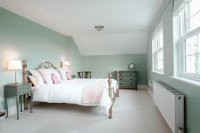 a bedroom with a bed with white sheets and pink pillows at The Green Door Vegan B&B in Llanon
