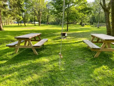 two picnic tables in the grass in a park at River View Glamping in Llandovery