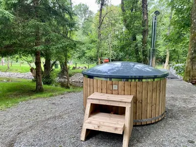 a wooden dog house with a wooden stool in a park at River View Glamping in Llandovery