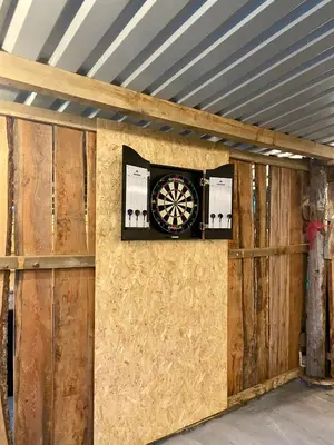 a dart board on the wall of a garage at River View Glamping in Llandovery