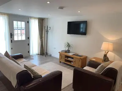 a living room with a couch and a tv on the wall at The Granary at Pentregaer Ucha, tennis court & lake. in Oswestry