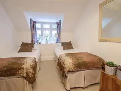 two beds in a room with a mirror and a window at Bodowen Coach House in Barmouth