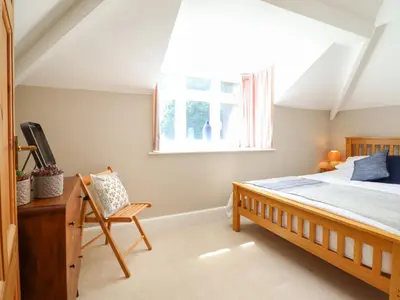 a bedroom with a bed and a window and a chair at Bodowen Coach House in Barmouth