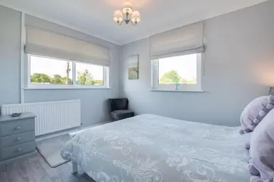 a white bedroom with a bed and two windows at 3 Bed in Aberaeron oc-bow330 in Ciliau-Aeron