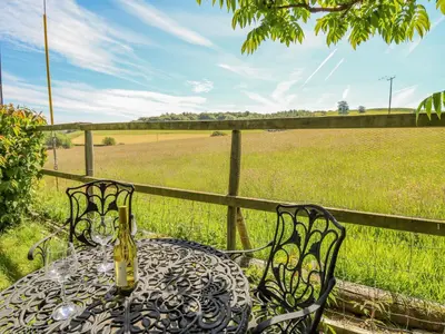 a table and chairs with a field and a fence at Bryniau Bychain Cottage in Machynlleth