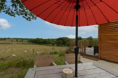 a red umbrella sitting on a table with two chairs at Blaenplwyf Shire Pods in Lampeter