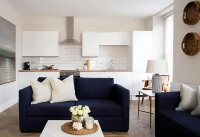 a living room with a blue couch and a kitchen at Salthouse apartment in Aberaeron