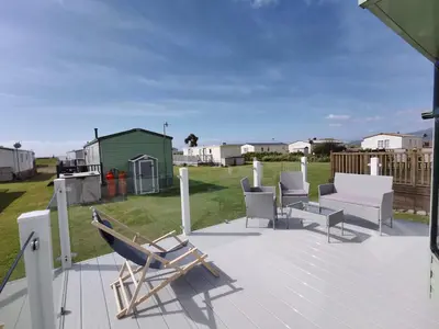 a patio with chairs and a hammock on a deck at Sea and Mountain view Sunbeach Holiday Snowdonia in Llwyngwril