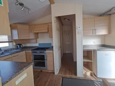 a kitchen with wooden cabinets and a stove top oven at Sea and Mountain view Sunbeach Holiday Snowdonia in Llwyngwril