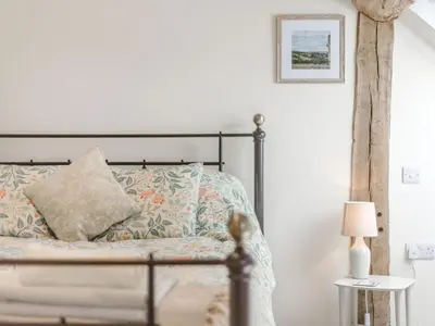 a bedroom with a bed with a pillow and a lamp at The Old Milking Parlour in Wentnor