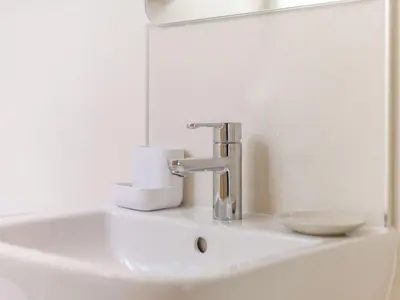 a bathroom sink with a faucet and a mirror at The Old Milking Parlour in Wentnor