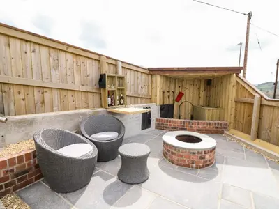 a patio with four chairs and a kitchen with a stove at The Old Cobblers Shop in Llandrindod Wells