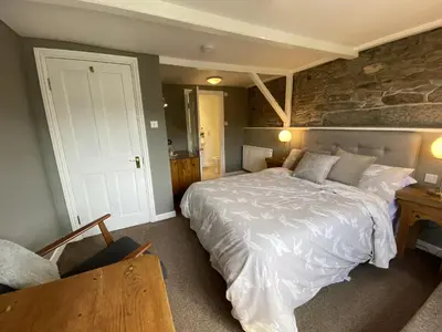 a bedroom with a large bed and a stone wall at Tom's of Tregaron in Tregaron