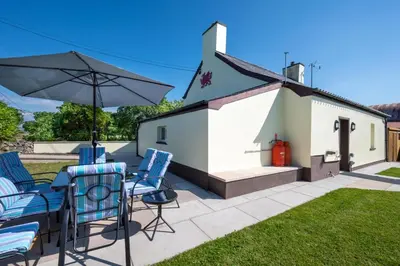 a group of chairs and an umbrella on a patio at 2 Bed in Tregaron oc-bow289 in Tregaron