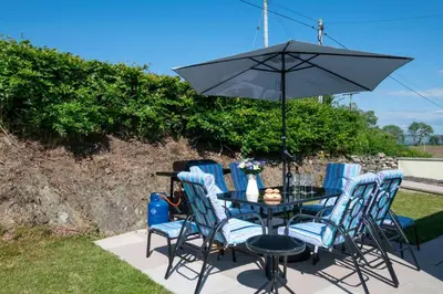a black table with blue chairs and an umbrella at 2 Bed in Tregaron oc-bow289 in Tregaron